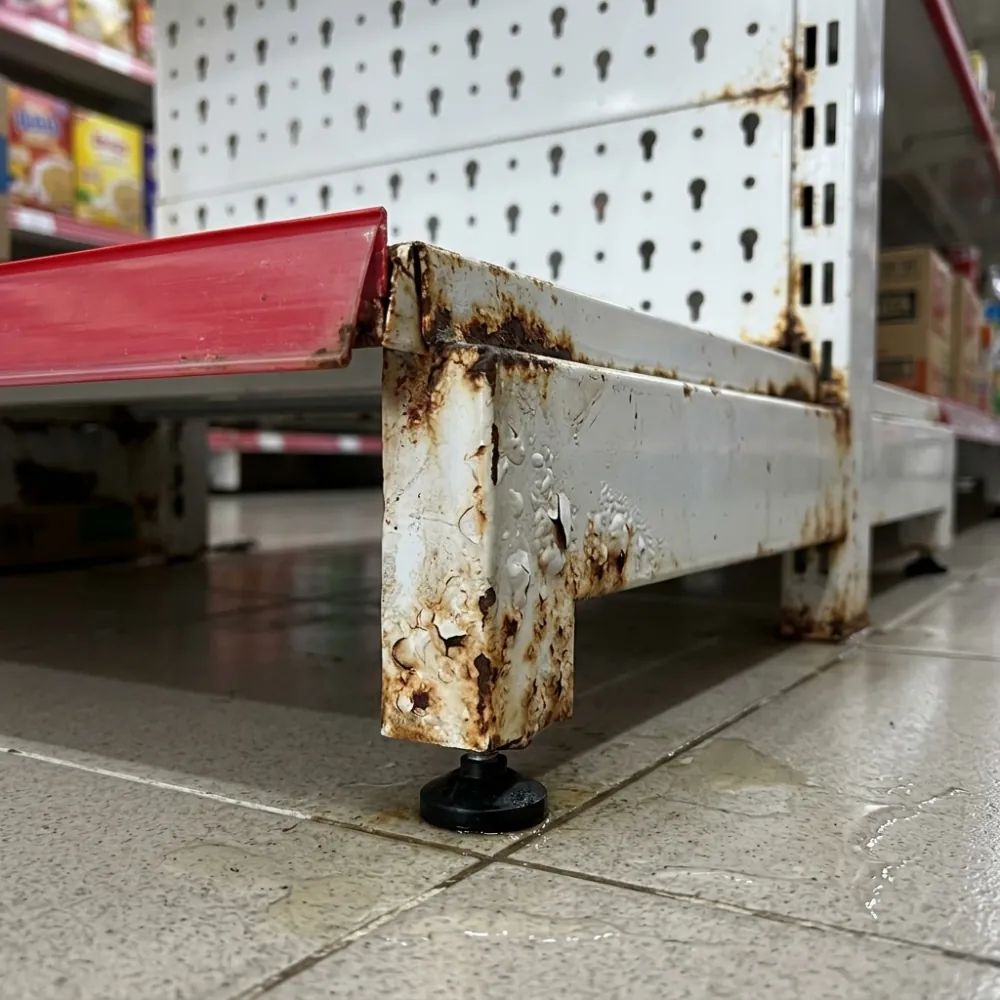 Chân trụ kệ siêu thị bị han gỉ, bong tróc sơn ở phần tiếp xúc với sàn ẩm